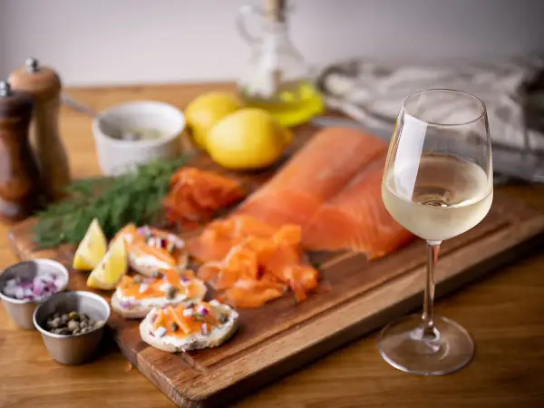 Un verre de vin blanc, parfait pour accompagner du saumon fumé, des toasts au fromage frais, câpres et oignons rouges.